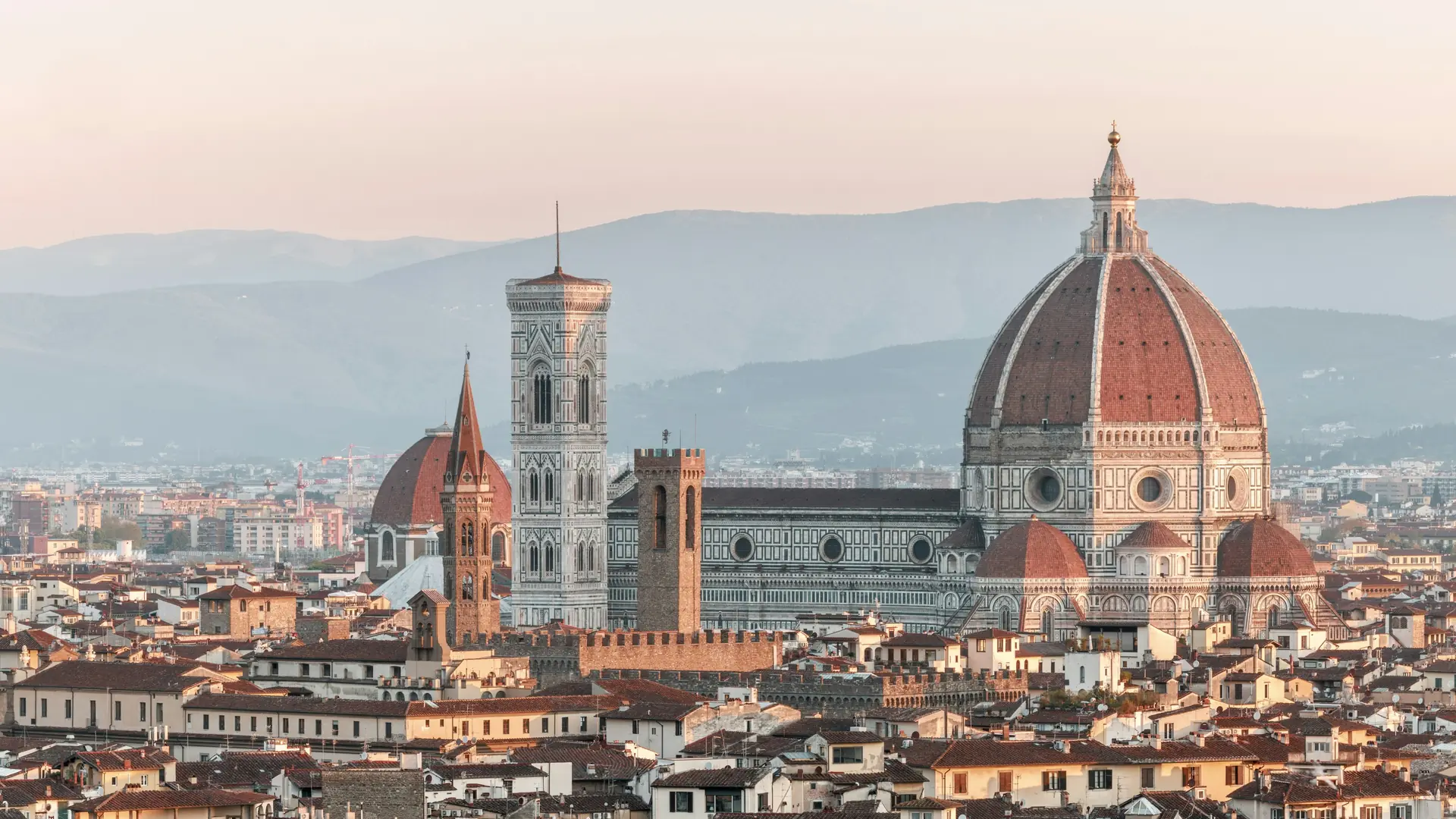 Brunelleschi's dome and Giotto's bell tower rising above Florence's rooftops in soft early light